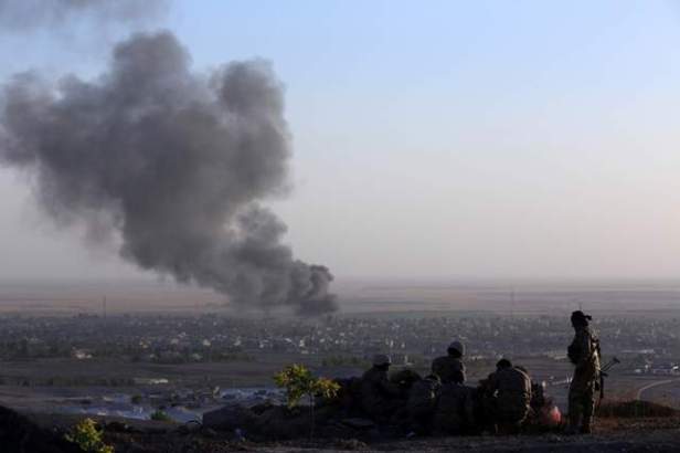 Iraqi Kurdish Peshmerga fighters look on as smoke billows from the town of Makhmur on Aug 9